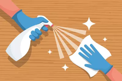 hands spraying and wiping wooden surface