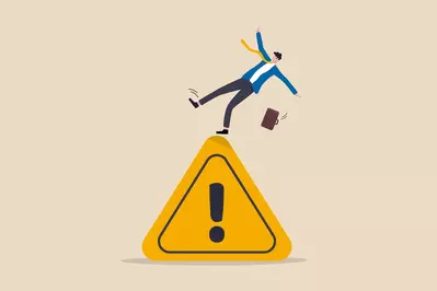 businessman tripping on caution sign to illustrate a mistake