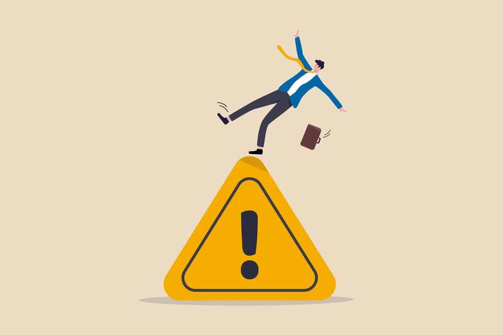 businessman tripping on caution sign to illustrate a mistake